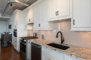 Sleek renovated kitchen with rich hardwood floors, a roomy central island with bar seating, and custom white cabinets