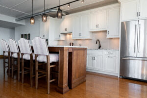 Updated kitchen design with dark hardwood floors, spacious island with seating, and elegant white cabinetry