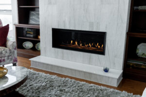 Detail of a renovated living room fireplace featuring a white tile mantle and dark custom wooden shelving on both sides
