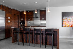 This renovated kitchen by R.E. McNamara Inc perfectly blends form and function. It features rich, dark cabinets complemented by durable and stylish light countertops and floors. The functional central island comes with a built-in sink and comfortable bar seating, making it an ideal hub for cooking and gathering.