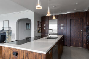 An inviting kitchen scene showcasing R.E. McNamara Inc's renovation skills, featuring sleek, dark cabinetry, stainless steel appliances, and light countertops and flooring, creating a harmonious blend of modern design elements.