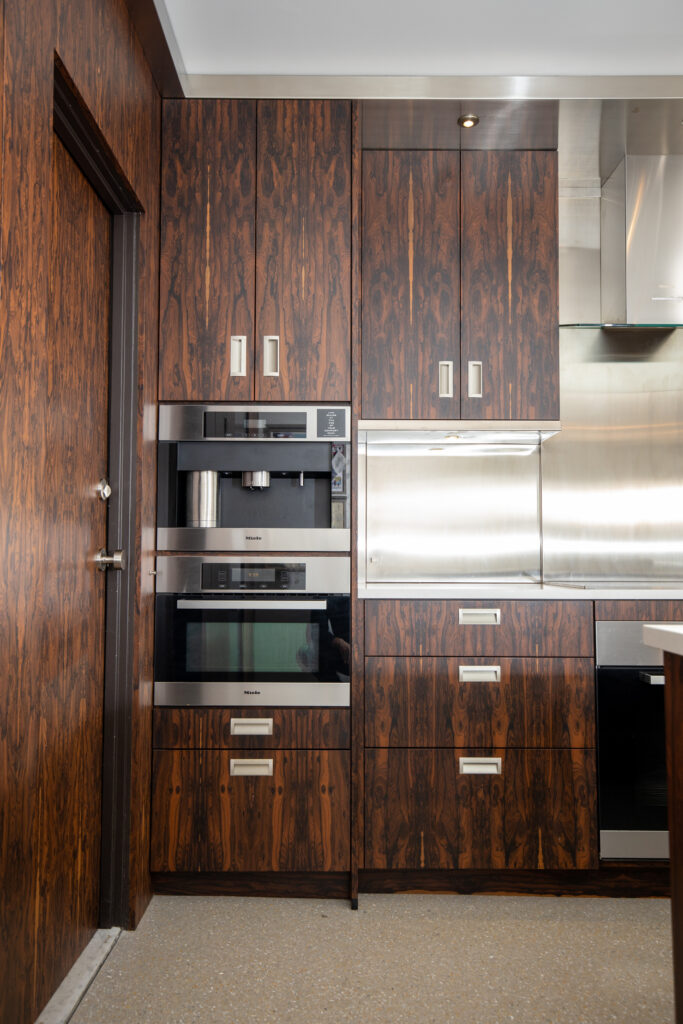 Stylish kitchen update with rich, dark cabinetry and contrasting stainless steel appliances, highlighting an oven, microwave, and functional backsplash.
