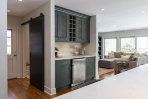Green kitchen cabinets featuring minifridge, wine storage, and mesh cabinets in a completed R.E. McNamara Inc. residential makeover.