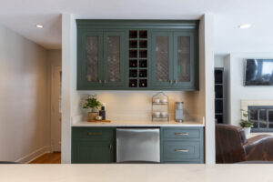 Stylish green kitchen cabinetry with built-in minifridge, wine storage, and mesh cabinets in a R.E. McNamara Inc. residential renovation project.