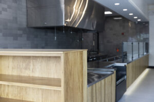 Renovated service counter at Rachel's Mediterranean Grill by R.E. McNamara Inc. featuring wooden pickup shelves.