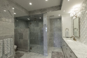 Stylish bathroom equipped with matching sinks for him and her, marble tilework on floors and walls, an eye-catching backsplash, and a sizable walk-in shower with a half wall division and tailored seat for convenience.