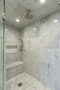 Refined bathroom encompassing a spacious walk-in shower including a privacy half wall and custom-built seating.