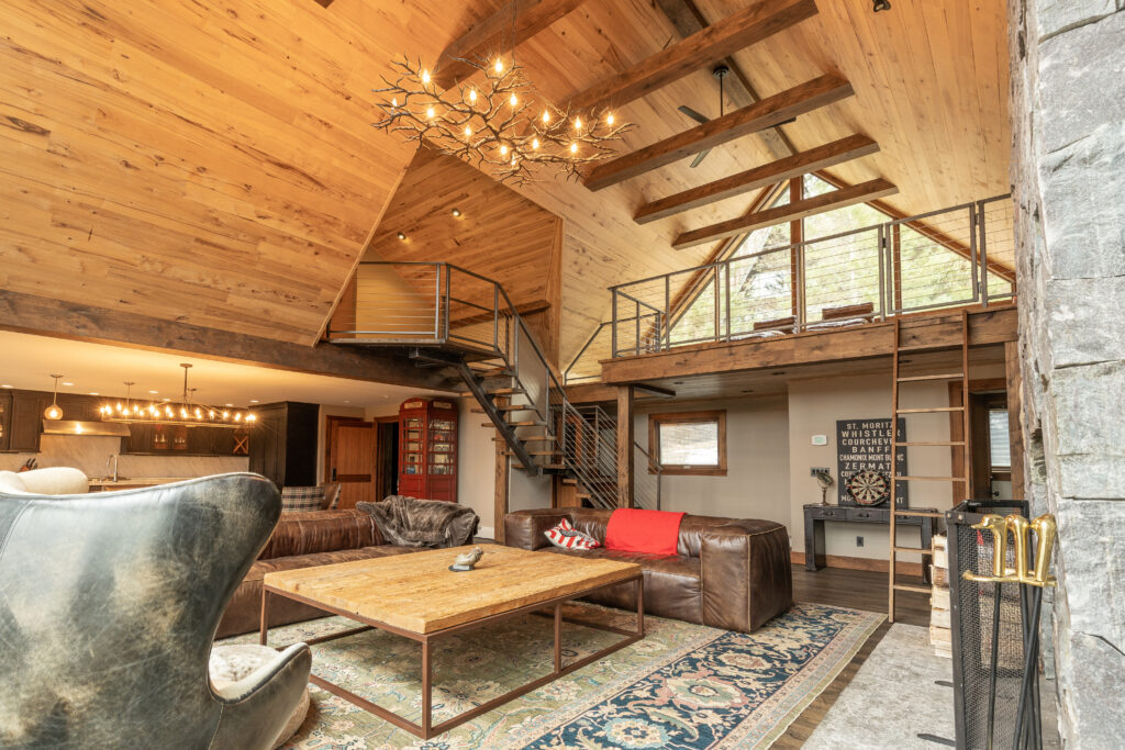 Spacious, modern living area with cream-colored walls, contrasting dark hardwood flooring, and custom wood-paneled ceiling, beautifully transformed by R.E. McNamara Inc.