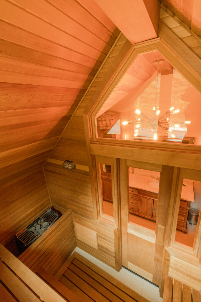 A cozy sauna room in a residential renovation project, featuring warm custom wood paneling lining the walls, creating a relaxing atmosphere for unwinding after a long day.