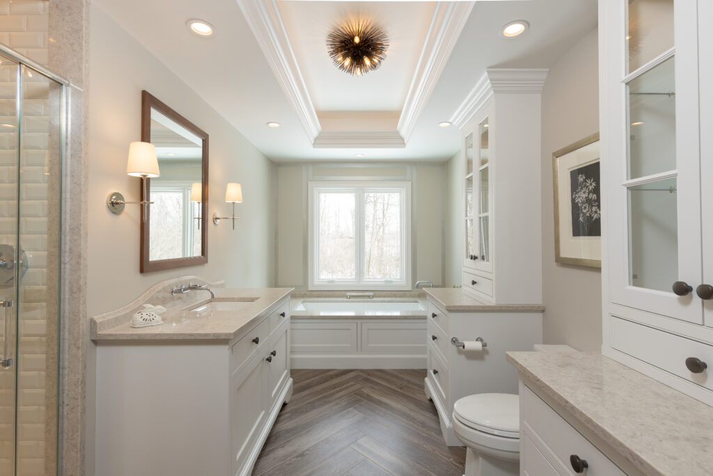 Elegant residential bathroom featuring white custom cabinetry, hardwood floors, and beige surfaces - renovated by R.E. McNamara Inc.