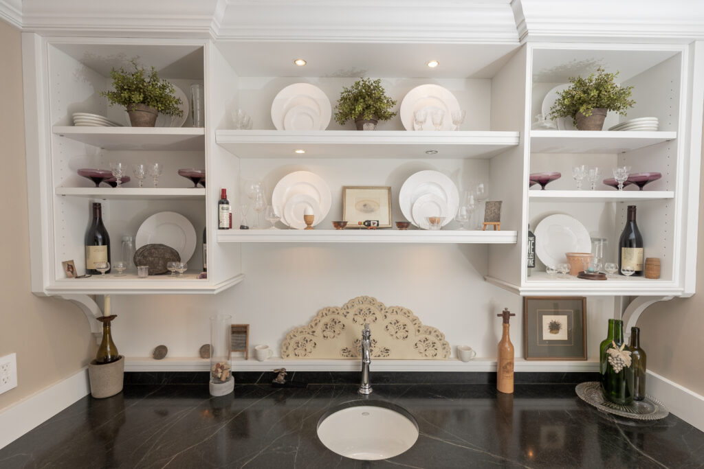 White custom shelving displaying items above a sleek sink, complemented by a black countertop, in a recently renovated residential space by R.E. McNamara Inc.