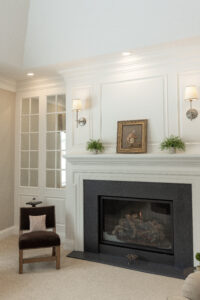 Elegant white custom woodwork encasing a fireplace in a beautifully renovated residential living room by R.E. McNamara Inc