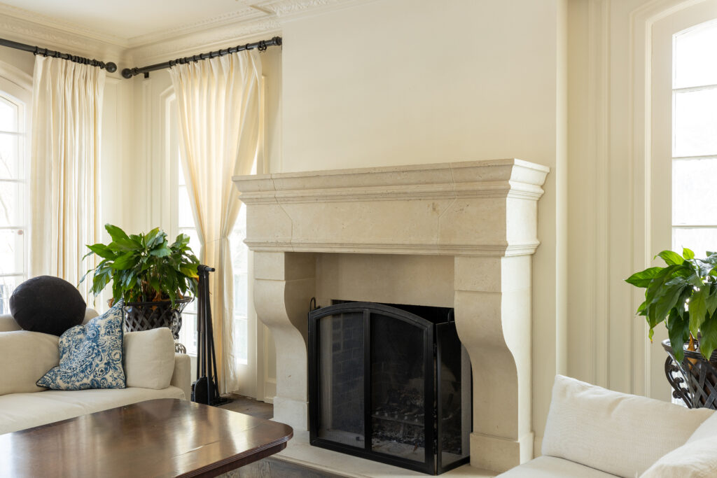 A white stone fireplace serves as the focal point in this elegant living room, featuring white walls and a beautiful blend of modern and cozy styles. Experience the expert craftsmanship and attention to detail R.E. McNamara Inc. brings to every residential renovation project.