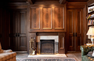 A stunning, cozy study room showcasing a warm, inviting fireplace nestled within rich, custom-designed dark wood paneling, expertly crafted by the experienced team at R.E. McNamara Inc.