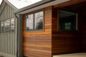 Exterior of a beautifully designed snow-covered house with custom wood paneling and dark vertical siding