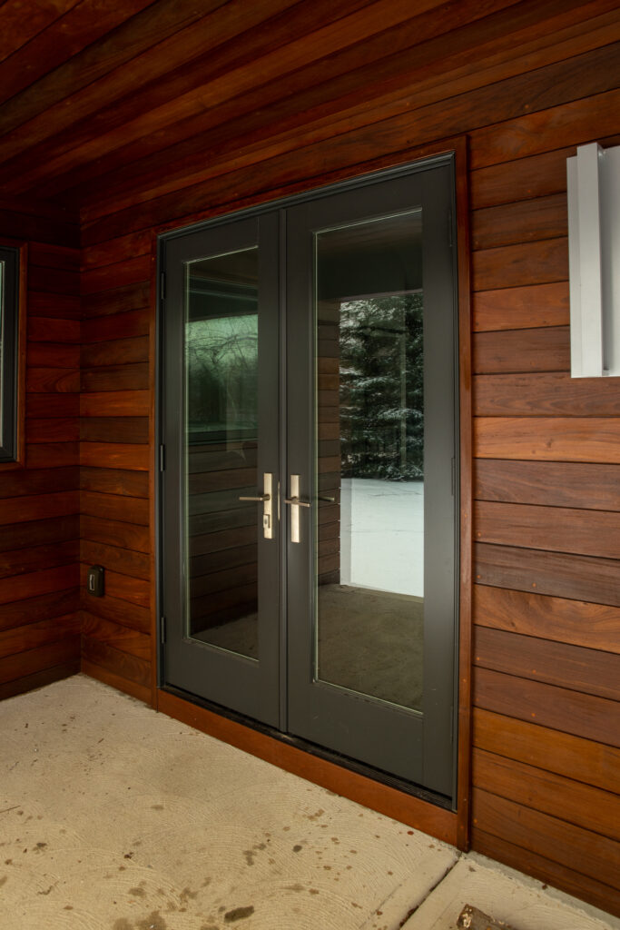 Exterior view of elegant double doors surrounded by custom wood paneling