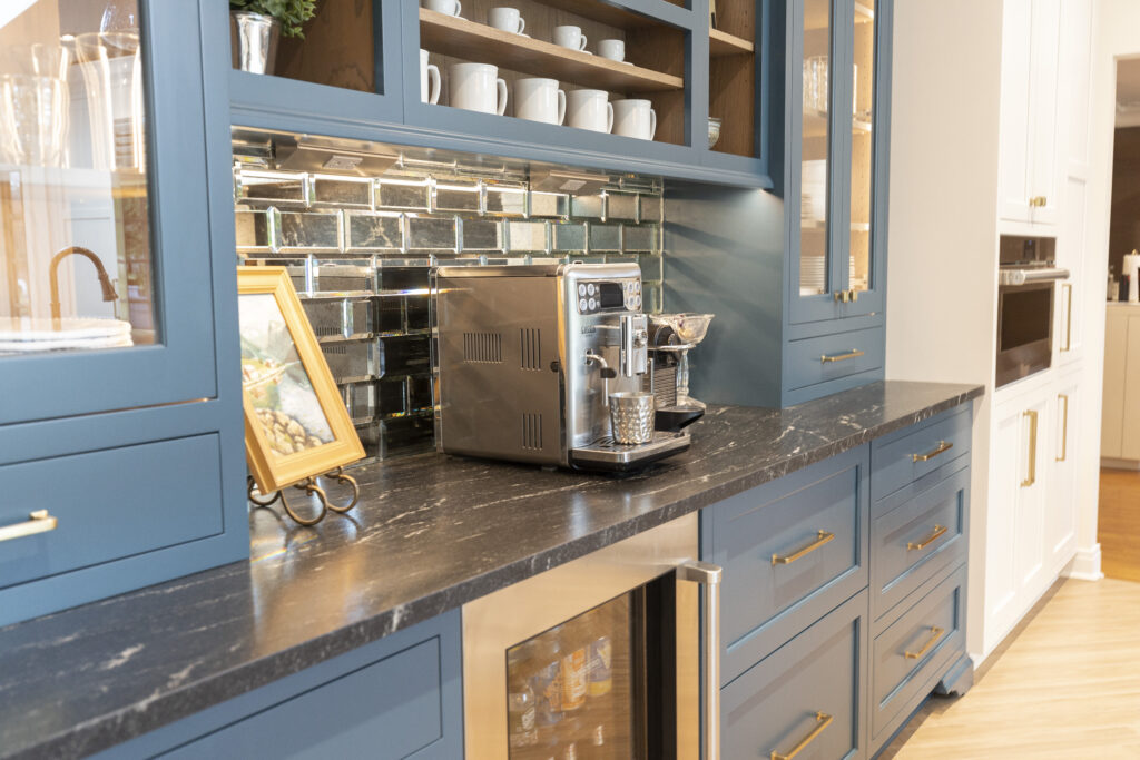 A strikingly vibrant blue custom cabinetry with sleek dark countertops, featuring a seamlessly integrated mini fridge, beautifully showcases the exceptional craftsmanship and attention to detail in R.E. McNamara Inc.'s residential renovation projects.