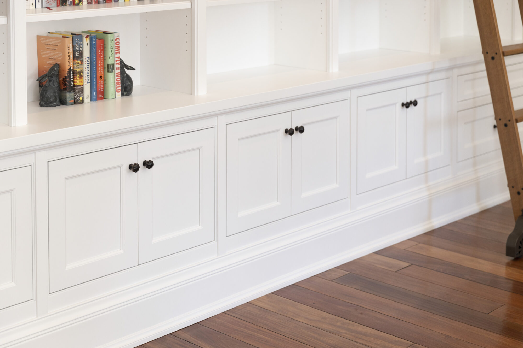Custom-built white cabinetry forms an elegant bookcase wall in a renovated residential space, reflecting R.E. McNamara Inc.'s expertise in design and craftsmanship.