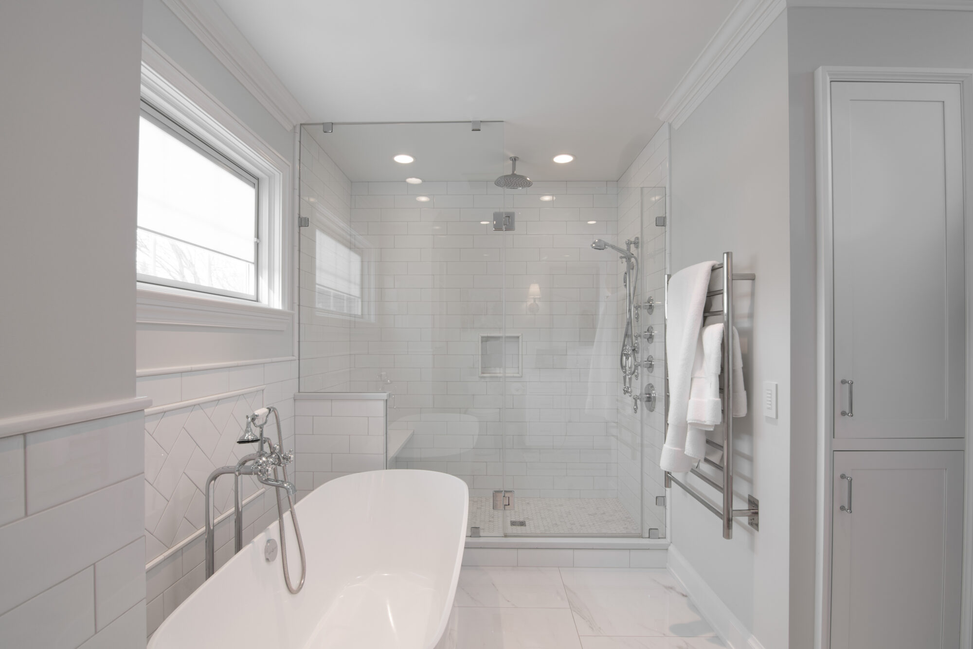 Elegant walk-in shower with an adjacent sit-in tub, both surrounded by pristine white tiling and flooring