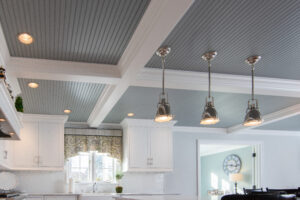 Completed residential renovation showcasing grey ceiling paneling, stainless steel lights, and white decorative beams