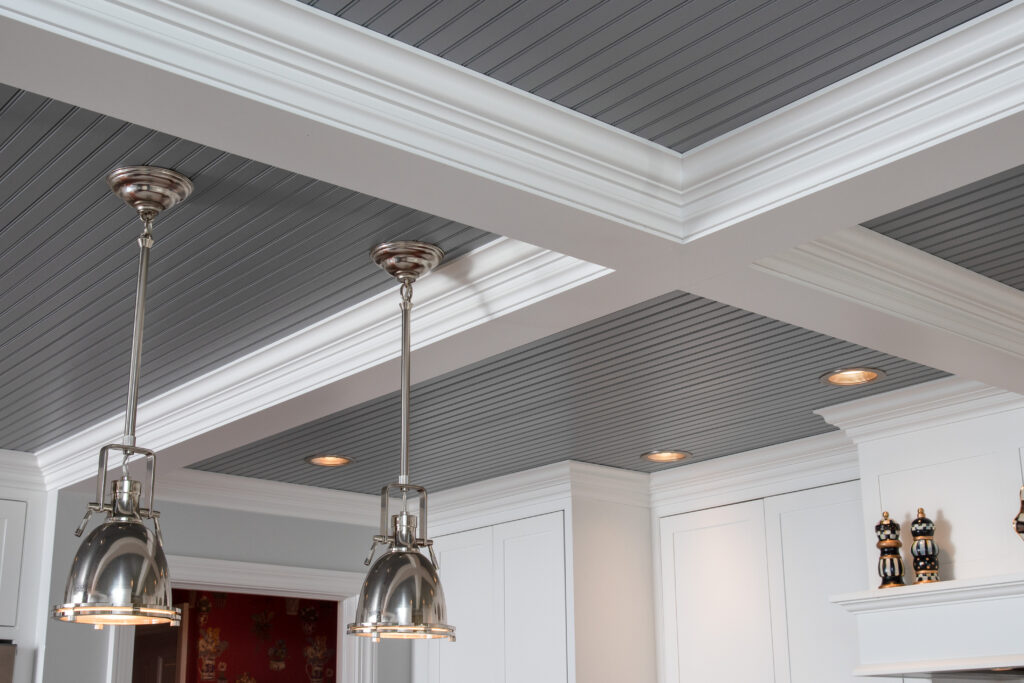 Grey paneling, stainless steel lights, and white decorated beams on the ceiling in a residential renovation project