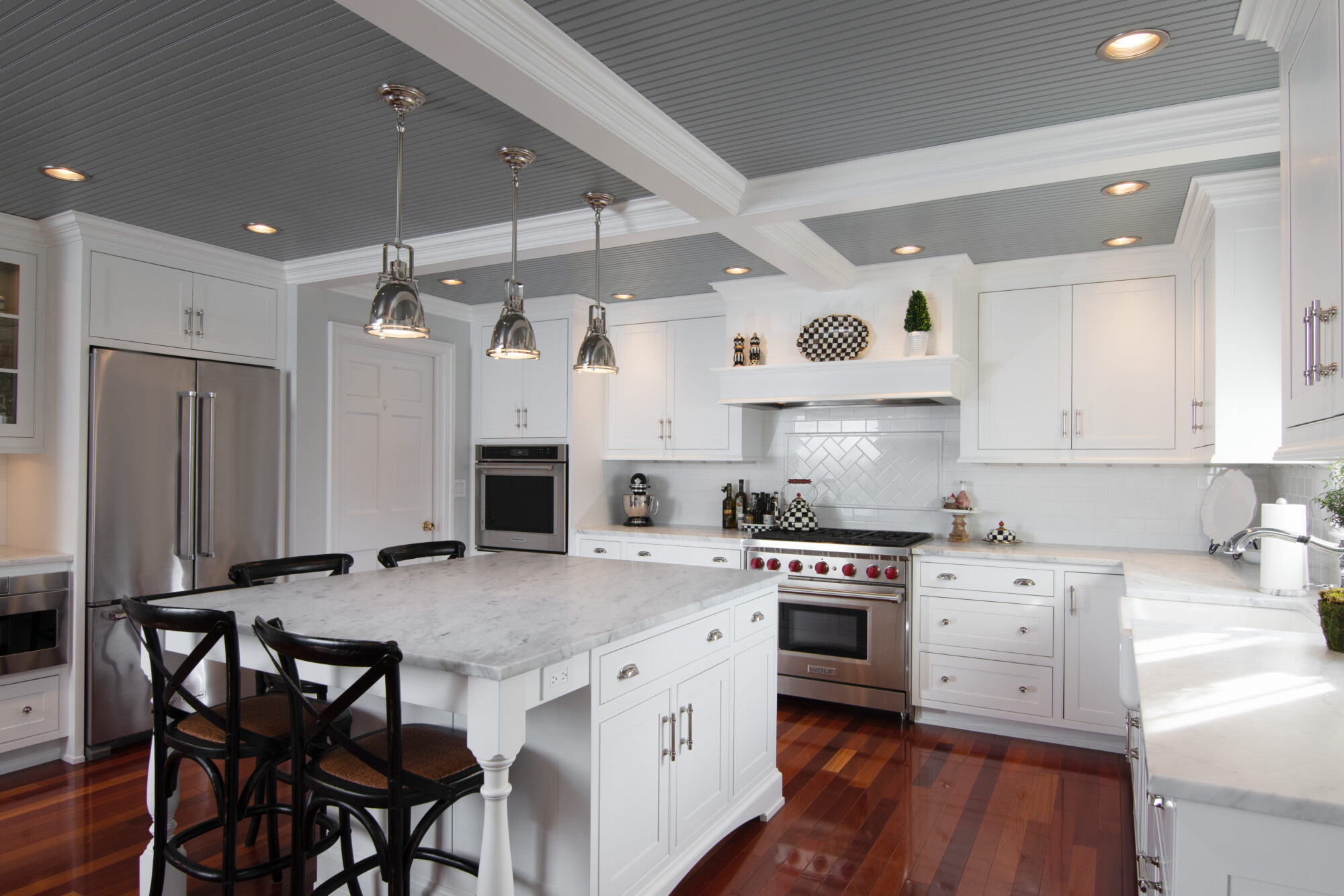 "R.E. McNamara's stunning kitchen transformation with bright white cabinets, elegant hardwood floors, and contemporary stainless steel appliances.