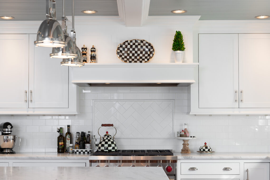 Beautiful R.E. McNamara renovated kitchen featuring white cabinets, white tile backsplash, and sleek stainless steel appliances.