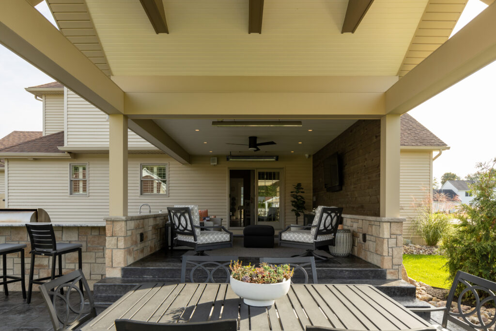 Outdoor covered residential patio by R.E. McNamara Inc., featuring a stainless steel grill, bar seating, and plenty of space to entertain.