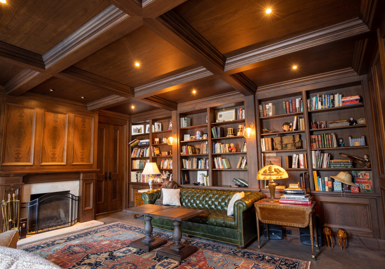 A stunning study room in a residential renovation project by R.E. McNamara Inc., featuring custom-made dark wood shelving filled with books, elegant ceiling accents, and a cozy central sofa that invites you to delve into a good read.